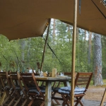 Турист с планшетом в палатке во время непогоды в горах